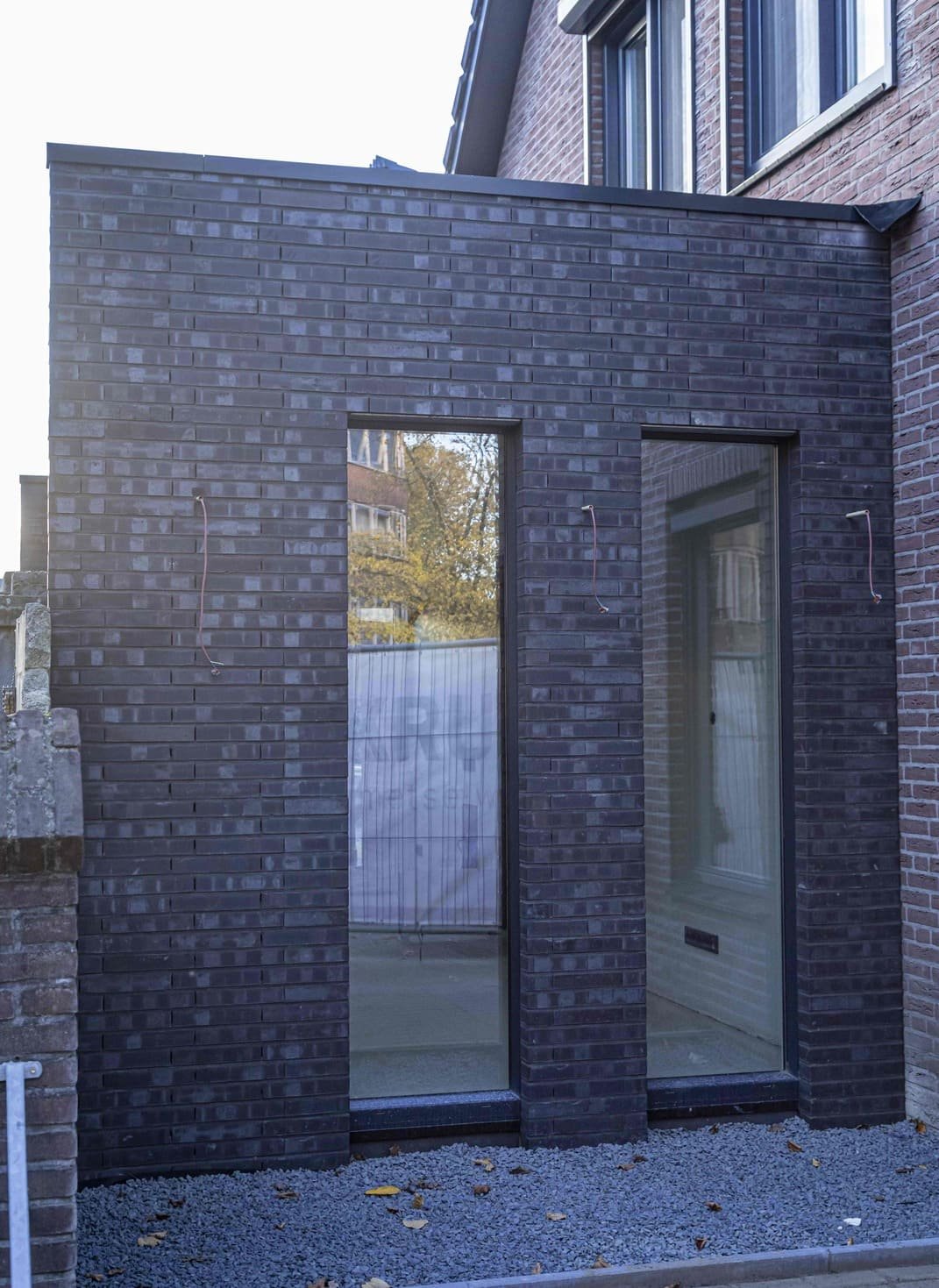 Donkere bakstenen aanbouw met grote ramen