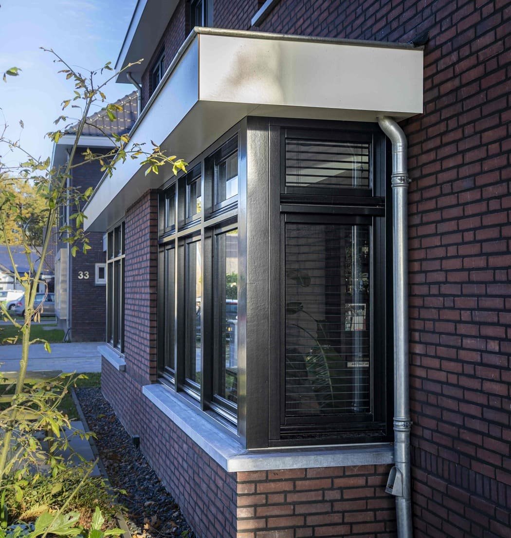 Grote raampartij met jaloezieën in een bakstenen muur